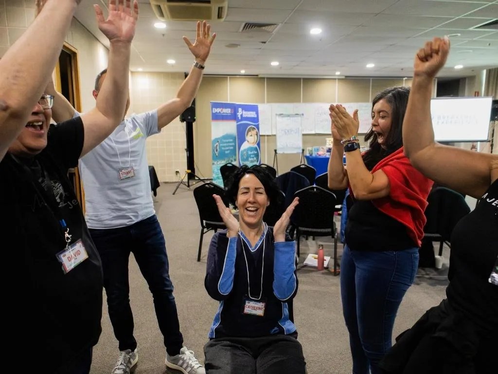 Adults on their feet, energised at a Break Free Experience event